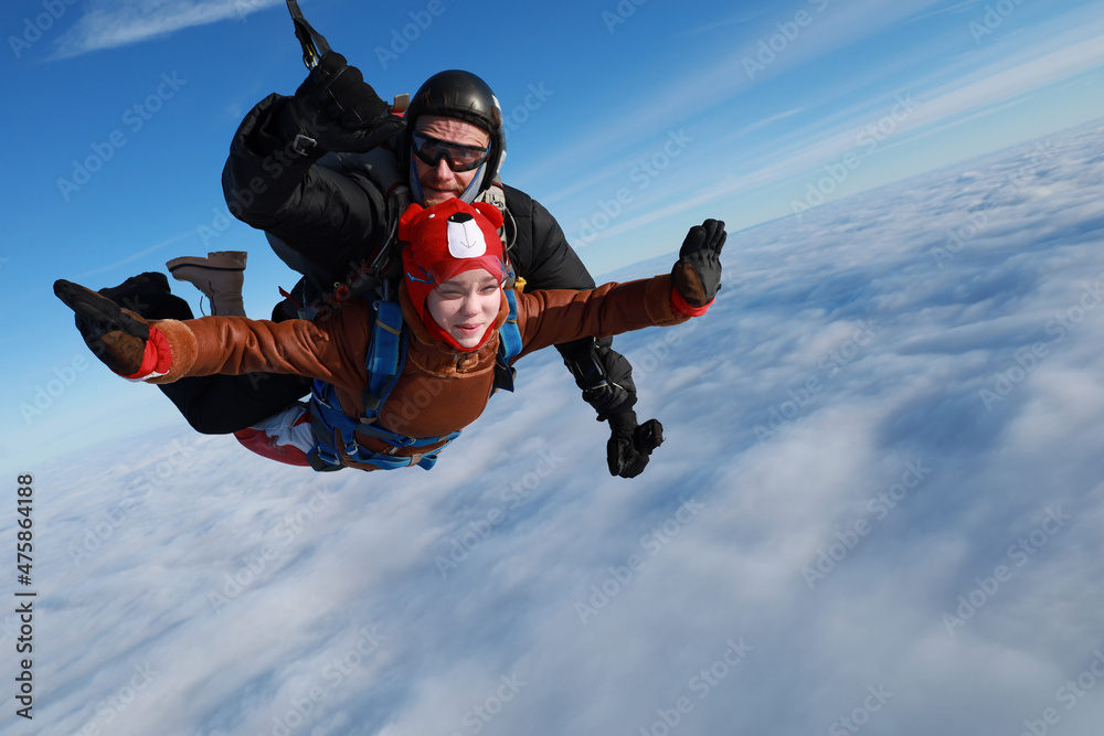 Skydiving. Tandem jump. A happy girl and her instructor are flying in the winter sky. Skydiving. Tandem jump. A happy girl and her instructor are flying in the winter sky.