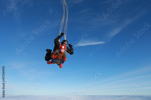 Skydiving. Tandem jump. A happy girl and her instructor are flying in the winter sky.