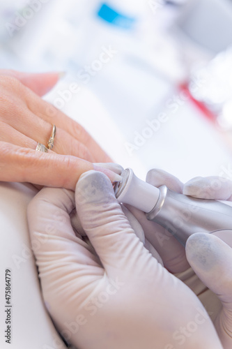 Close up verical photo of manicurist with Electric Nail Drill in Beauty Manicure Salon