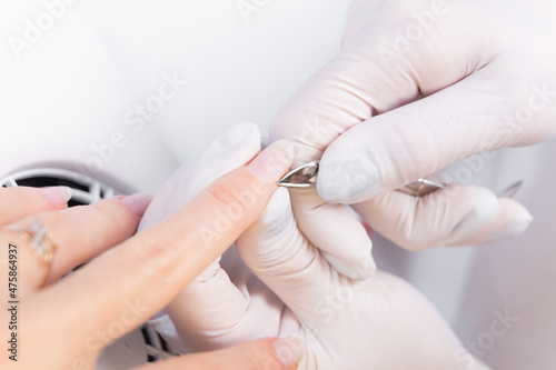 manicurist uses cuticle scissors to process a client s manicure in a beauty salon