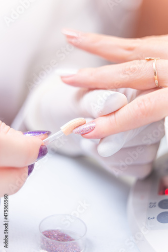 applying bright glitter on a customer s nails in a beauty studio