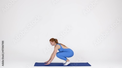 Sporty young female making burpee exercise on fitness mat in studio photo