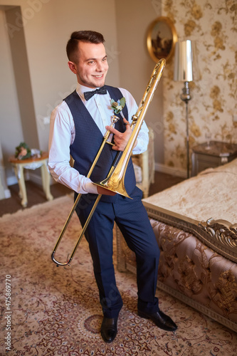 Young groom professional trumpeter holding a trumpet in his hands.