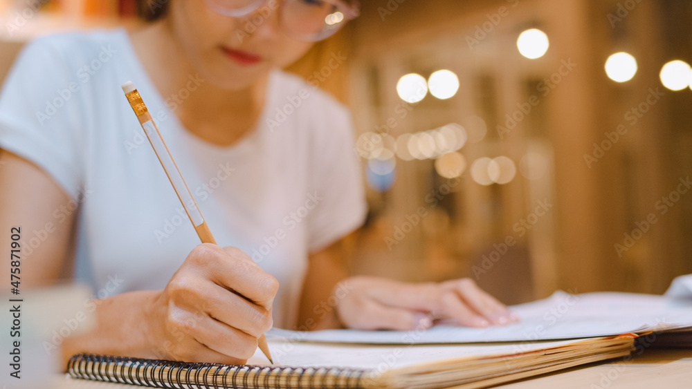 Asian student women reading books in library at university. Young undergraduate girl do homework, read textbook, study hard for knowledge on lecture desk at college campus overtime night. Asian student women reading books in library at university. Young undergraduate girl do homework, read textbook, study hard for knowledge on lecture desk at college campus overtime night.