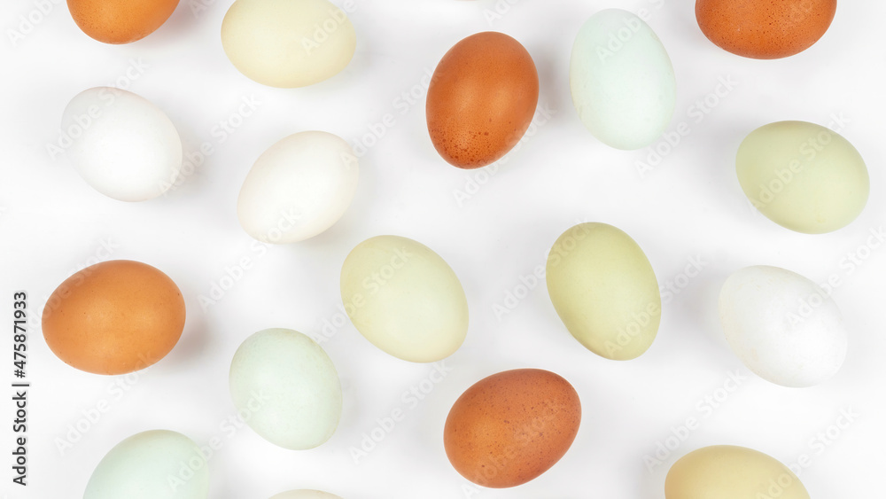 Chicken eggs pattern top view. Organic eggs scattered on a white background. Chicken Easter eggs banner with copy space.