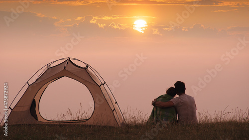 The romantic couple sitting at the campsite on a beautiful sunset background