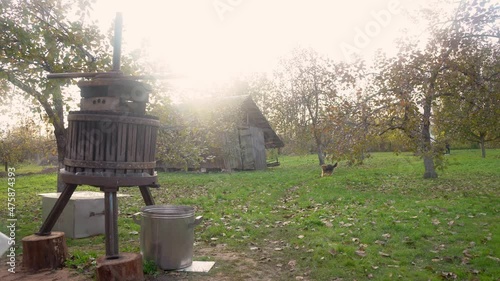 Harvesting fruit juice at home using the old method. Beautiful rural autumn landscape with a shaggy dog old decayed abandoned wooden barn next to a beautiful garden with autumn colours at sunset 4k