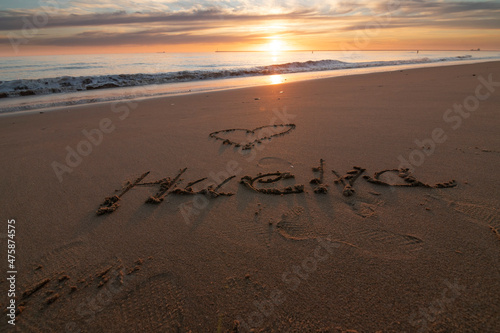 A beautiful sunset on the beach of Mazagon, Spain. In the sand written the word Huelva, Spanish province.