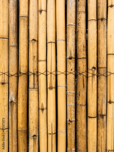 Old brown tone bamboo simple wall or Bamboo fence texture background for interior or exterior design vintage tone. Brown bamboo stick pattern backdrop. Local area urban house protection from thief.