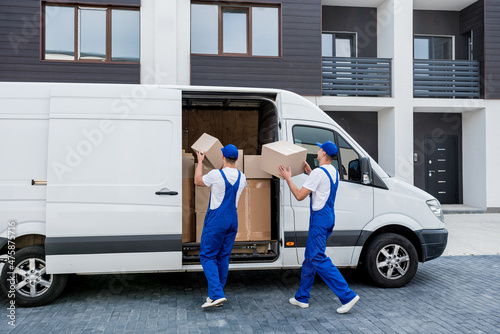 Two removal company workers unloading boxes from minibus into new home