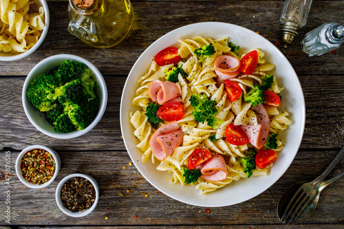 Obraz na plátně Pasta with ham, broccoli and cherry tomatoes  on wooden table