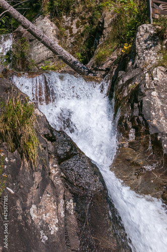 kleiner Wasserfall in bergiger und waldiger Landschaft an einem sonnigen Herbsttag © lucky  photographer
