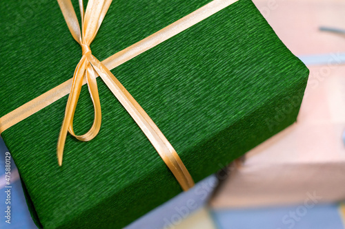 A green gift box tied with a yellow ribbon. Present for christmas, new year or birthday.