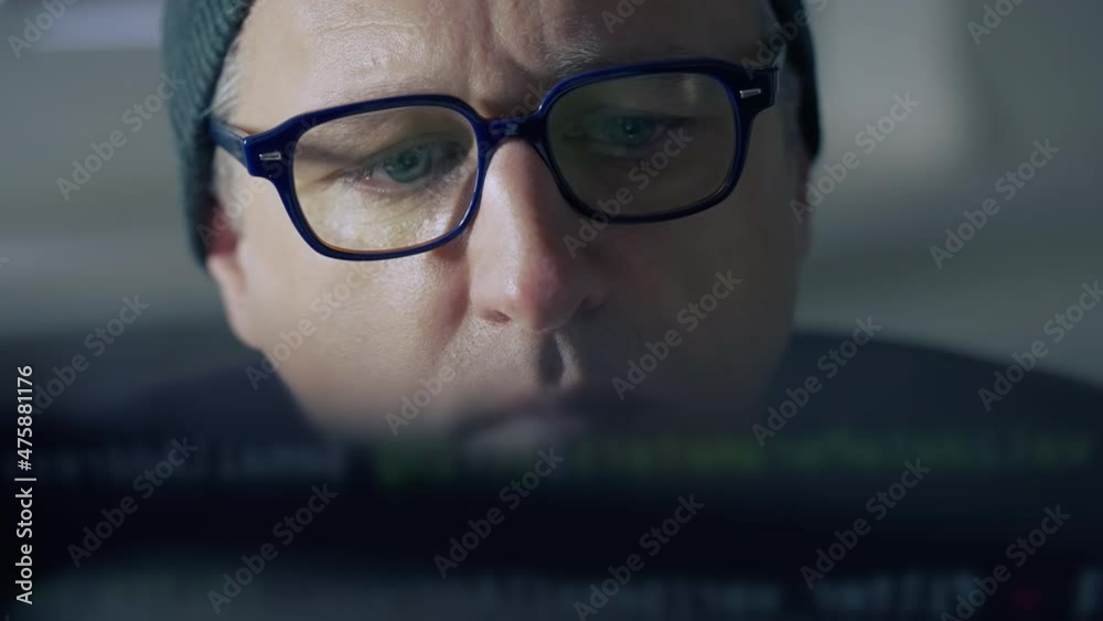 Furtive man hacking into a computer in close up Furtive man hacking into a computer in close up