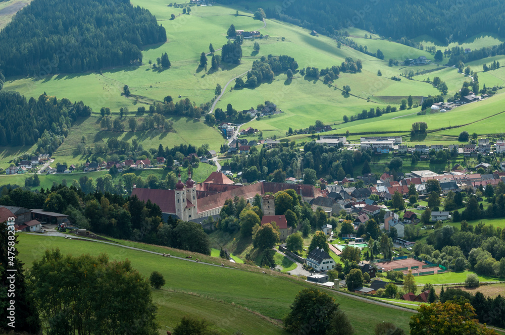 Blick auf einen Ort in der Steiermark, der in einem Tal liegt. Zentral ein Gebäude der Kirche