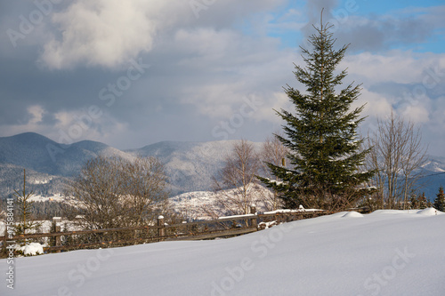 Winter remote alpine mountain village outskirts, countryside hills, groves and farmlands.