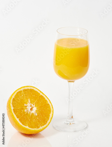 freshly squeezed orange juice in a glass and half an orange