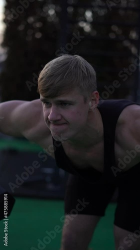 Caucasian white muscular man lifting dumbbells against the sunset sky background. Concept of desire, will and potential. 4k vertical footage 