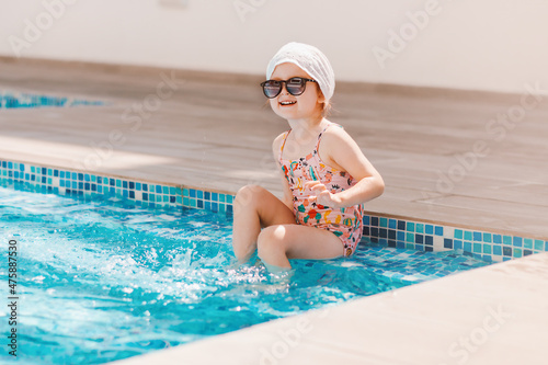 Cute toddler girl wear swimsuite having fun in pool with blue clean water. Family vacation in luxury resort © Nadezhda
