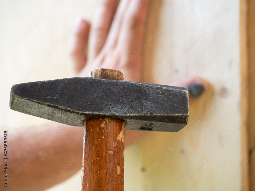 A closeup of an employee missed with a hammer and hit his finger