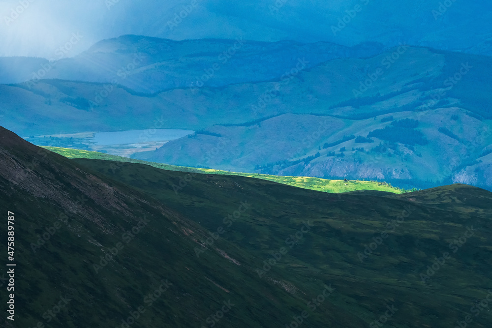 Selectiv focus. Evening mountains. Atmospheric landscape with silhouettes of mountains on background. Sundown in blue, green faded tones.