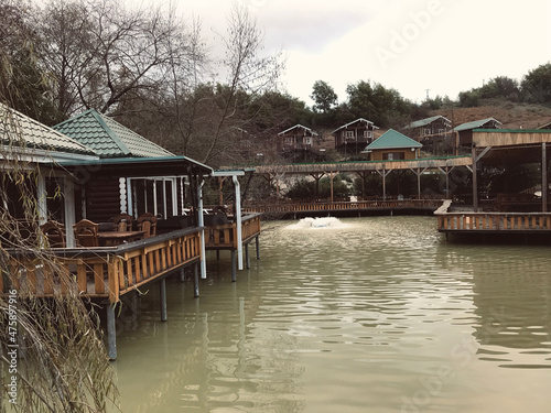 Street cafe with simple wooden interior on the shore of a picturesque lake. Authentic cafe with wooden tables and chairs near the Achigvar lake. Part of the terrace of the summer restaurant behind a w