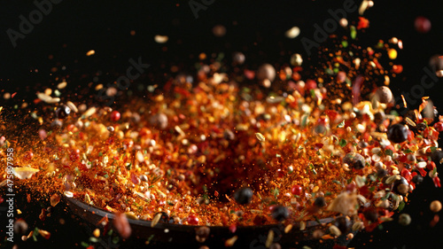 Freeze motion of flying mix of spice on black background. © Jag_cz