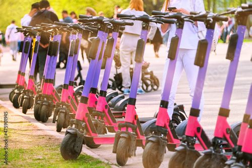 Electric scooters are parked in the parking lot on a summer day. Ecological transport in the park.
