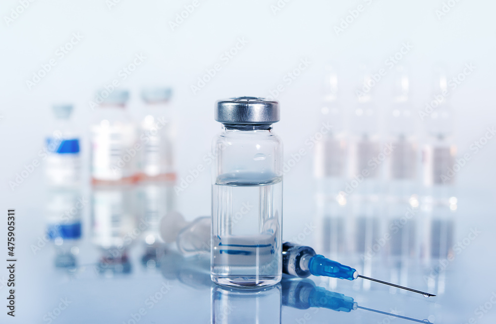 syringe and diferent kind of ampoules and vials close-up on white background with reflection syringe and diferent kind of ampoules and vials close-up on white background with reflection