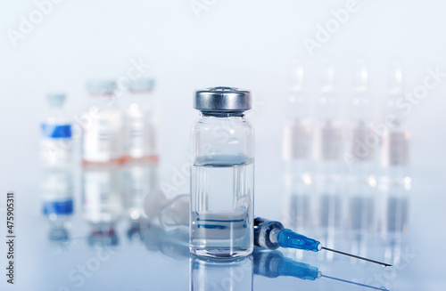 syringe and diferent kind of ampoules and vials close-up on white background with reflection