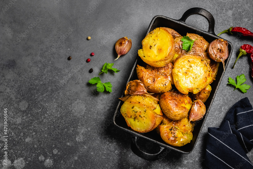Garlic butter smashed oven baked roast potatoes in cast iron skillet on
