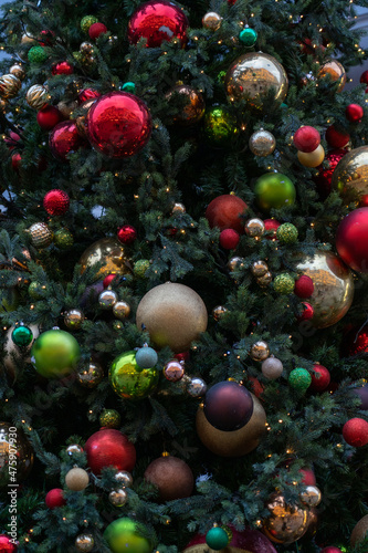 Close up view of Christmas tree branch with decorative balls  toys and shining garland. christmas tree decorations baubles and lights on city market street