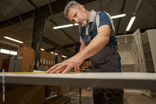 Serious grey-haired carpenter working in furniture manufacture