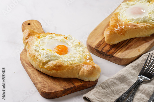 Traditional georgian dish of cheese-filled bread adjarian khachapuri with fried egg on a wooden board photo