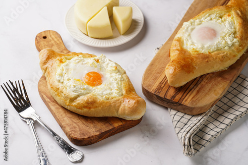 Traditional georgian dish of cheese-filled bread adjarian khachapuri with fried egg on a wooden board photo