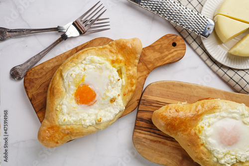Traditional georgian dish of cheese-filled bread adjarian khachapuri with fried egg on a wooden board photo