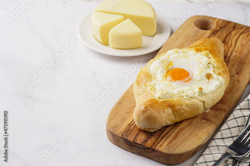 Traditional georgian dish of cheese-filled bread adjarian khachapuri with fried egg on a wooden board photo