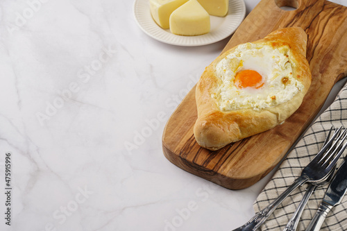 Traditional georgian dish of cheese-filled bread adjarian khachapuri with fried egg on a wooden board photo