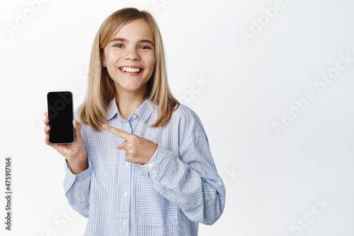 Little girl, blond teen child showing empty phone screen, mobile phone interface, video game on application, standing happy against white background