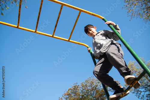 Argentinian boy playing at a monkey bar in a park photo