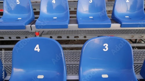 Grandstand seats - numbered temporary retractable seating. Modular stands with numeration for audience on a stadium. Convertible and removable empty bleachers (plastic chairs) for a concert event. photo