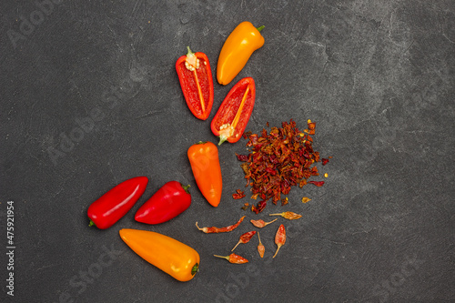 Fresh red and yellow peppers, nuts, dry pods and pepper petals on table.
