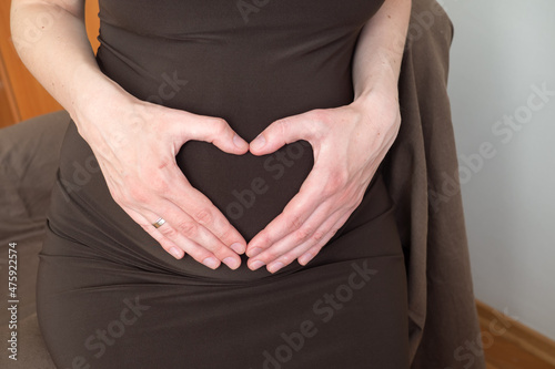 Pregnant woman make heart shaped hand sign show love to you in the womb of her. healthy motherhood and pregnancy
