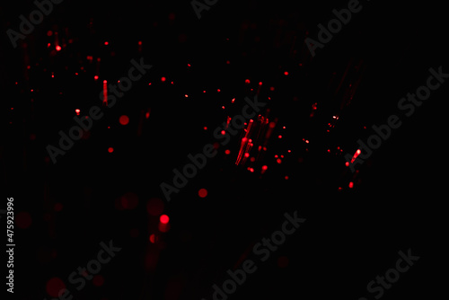 Glittering festive red and black background. Concept of New Year celebration. defocused blurred background. Sparkling magical dust particles.