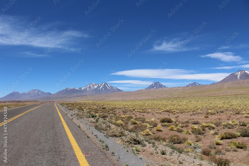 Empty highway road in the Atacama desert near San Pedro de Atacama with volcanos on the background.