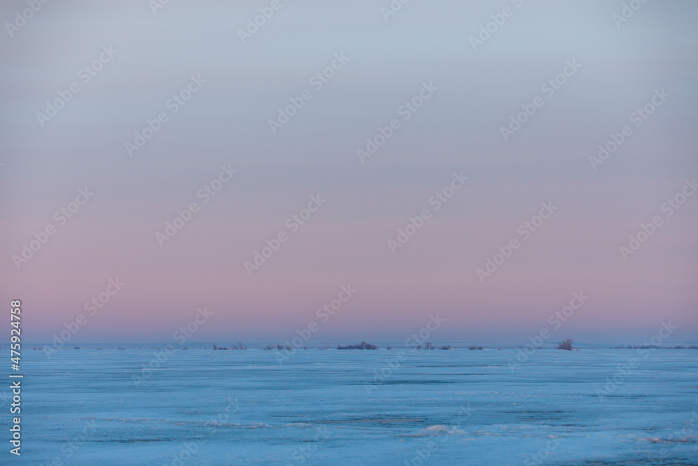 Lake Khanka in the Primorsky Territory in winter. View from above. Frozen coast of a large lake. Arctic landscape. Picturesque ice lake during sunset.