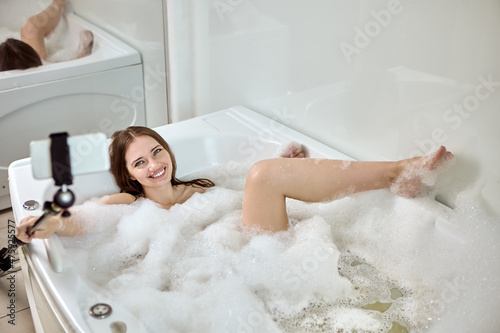 Hot whirlpool bath and selfie stick held by young woman.