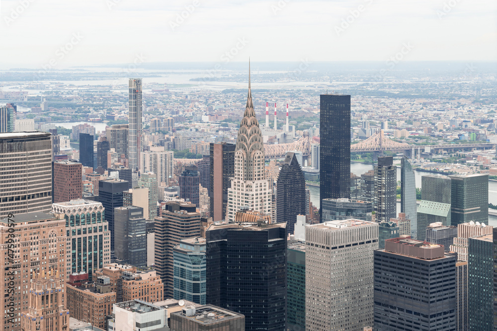 Zoom in aerial panoramic city view of Upper Manhattan area, the East Side, river and Brooklyn neighborhoods on horizon, New York city, USA. Iconic cityscape of building exteriors of NYC