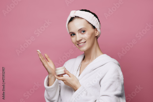 Fotografija Young girl in bathrobe holding face cream