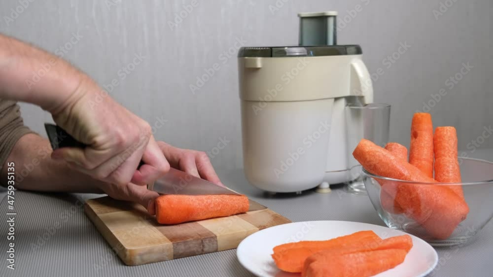 Vidéo Stock 4K Preparation of carrot juice in a juicer. A man cuts